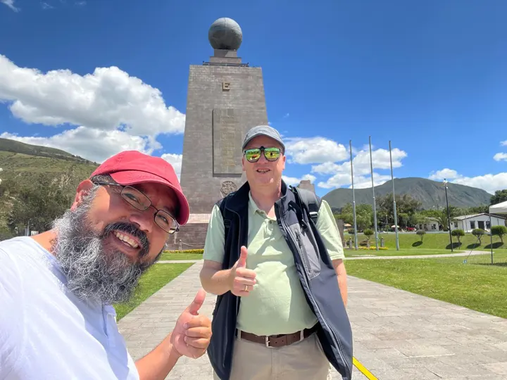 Monumento de la Mitad del Mundo con visitante sobre la línea ecuatorial